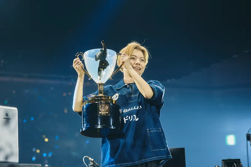 Capcom Cup 12 champion SAHARA holding the trophy in an official Capcom event photo.